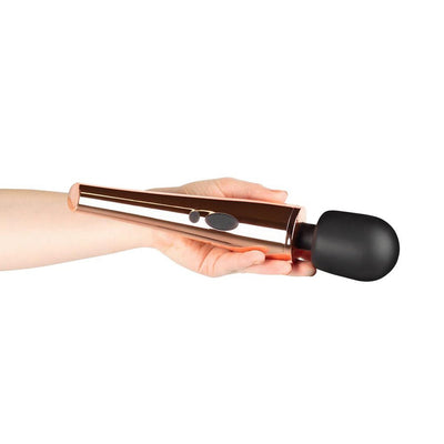 Hand holding a sleek rosy gold wand massager with a black flexible head and control buttons on the handle.