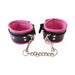 Black and pink padded leather wrist cuffs connected by a detachable silver chain with trigger hooks.