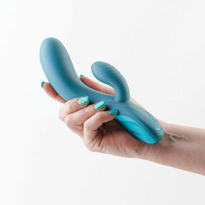 Hand holding a teal Royals Regent Rabbit Vibrator with ergonomic design and smooth silicone finish against a white background.