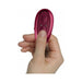 Hand holding a small, sleek metallic red remote control for the Ruby Glow Rosa Saddle Vibrator.