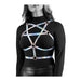 Rainbow holographic chest harness with rose gold hardware worn over a black long-sleeve top and leather pants.