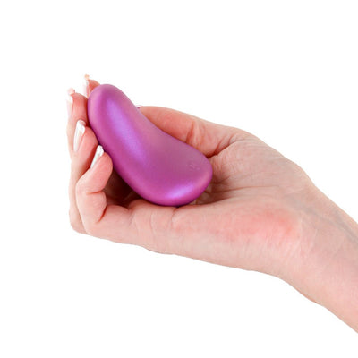 Hand holding a compact, curved metallic purple personal massager with a smooth, ergonomic design.