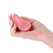 Hand holding a compact, smooth pink metallic personal massager with an ergonomic curved design.