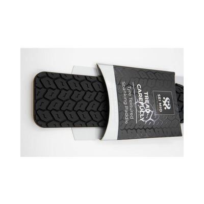 Black Sei Mio Tyre Paddle with textured tire tread pattern partially wrapped in branded packaging.