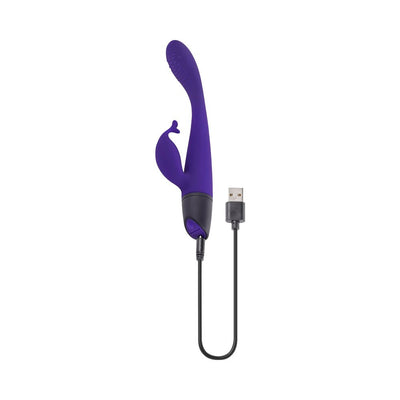 Purple dual stimulator with curved textured tip and flexible tickler, shown with USB charging cable attached.