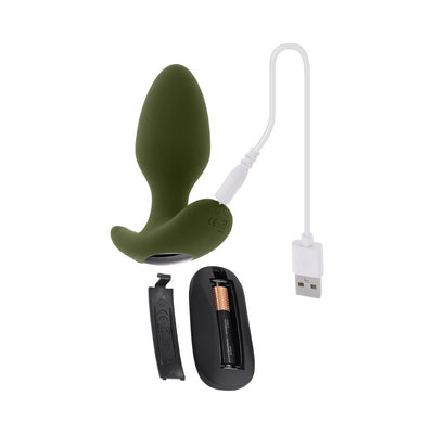 Green silicone vibrating plug with remote control, USB charging cable, and open battery compartment shown on white background.