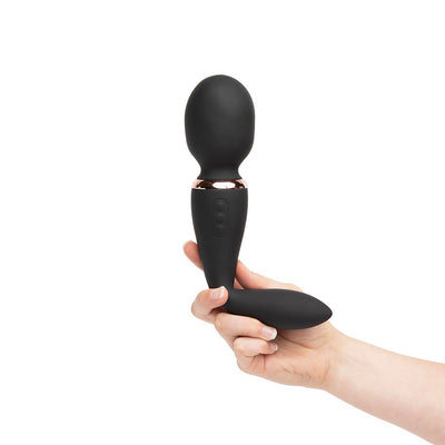 Hand holding a black Sensuelle Xlr8 Alluvion dual-ended wand vibrator with curved handle and rounded head.