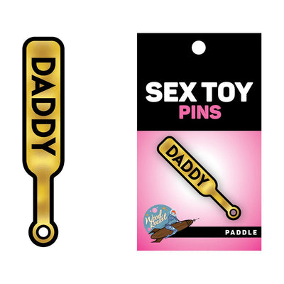 Gold enamel pin shaped like a paddle with the word "DADDY" in bold black letters on packaging.