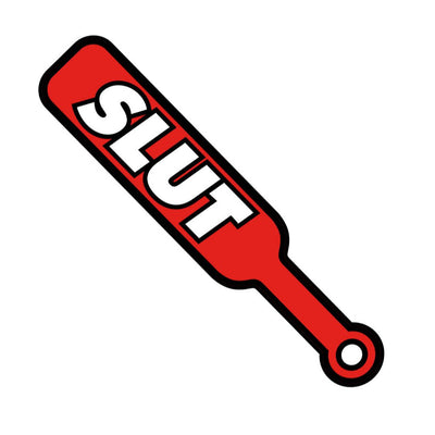 Red enamel lapel pin shaped like a BDSM paddle with bold white text reading "SLUT" and a small handle hole.