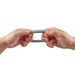 Hands stretching a small gray flexible silicone Shaft C-ring with embossed logo on white background.