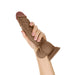 Hand holding a 10.5-inch realistic brown liquid silicone dildo with suction base and textured shaft.