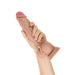 Hand holding a realistic 10.5-inch liquid silicone dildo with suction cup base and detailed texture.