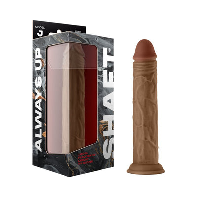 Shaft Model J 9.5-inch liquid silicone dildo in brown with realistic texture and suction cup base next to its packaging.