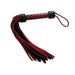 Short suede flogger with red and black tails and a checkered leather handle with wrist loop.