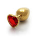 Medium gold aluminum butt plug with a red heart-shaped gem base on a white reflective surface.