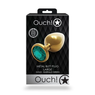 Packaging of Shots Ouch! large gold metal butt plug with emerald green jewel base on black diamond pattern background.