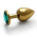 Large gold-toned metal butt plug with a smooth finish and a green jewel base, designed for comfortable wear and easy insertion.