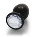 Large black metal butt plug with a clear faceted gem base, smooth rounded shape and tapered tip.