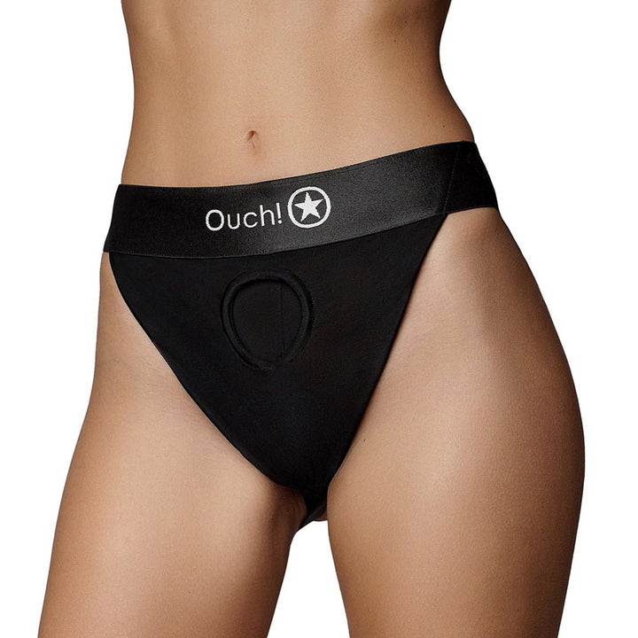 Black vibrating strap-on panty harness with Ouch! logo and front O-ring opening, worn on model's hips.