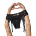 Black vibrating strap-on thong with adjustable garters held by hands forming a heart shape above it.