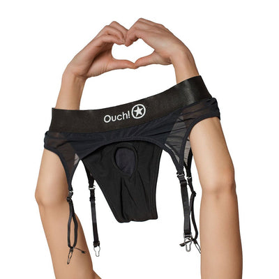 Black vibrating strap-on thong with adjustable garters held by hands forming a heart shape above it.