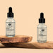 Two clear glass dropper bottles of Eye of Love Natural Pheromone Beard and Hair Oil on wooden platforms with beige background.
