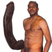 Lifelike 13.5-inch chocolate-colored ULTRASKYN dildo with textured veins and removable suction cup next to shirtless man.