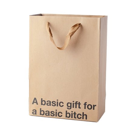 Kraft paper gift bag with brown ribbon handles and bold black text reading a basic gift for a basic bitch.