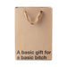 Kraft paper gift bag with brown ribbon handles and bold black text reading a basic gift for a basic bitch.