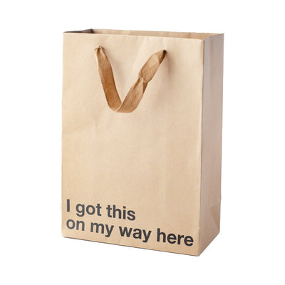 Kraft paper gift bag with brown ribbon handles and black text reading I got this on my way here, 11 x 8 x 4 inches.