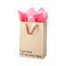 Kraft gift bag with brown ribbon handles and pink tissue paper, printed with "I got this on my way here" text.