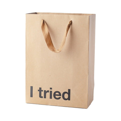 Kraft paper gift bag with brown ribbon handles and bold black text reading I tried on front