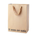 Brown kraft gift bag with brown ribbon handles and "It was on sale" printed in black text at the bottom front.