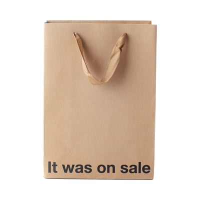 Brown kraft gift bag with brown ribbon handles and "It was on sale" printed in bold black text at the bottom.