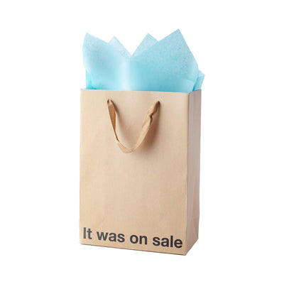 Brown kraft gift bag with brown ribbon handles and blue tissue paper, printed with "It was on sale" text at the bottom
