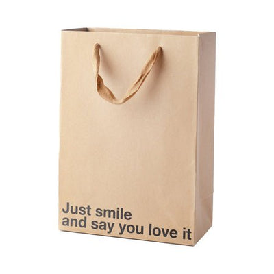 Kraft paper gift bag with brown ribbon handles and "Just smile and say you love it" printed in black text.