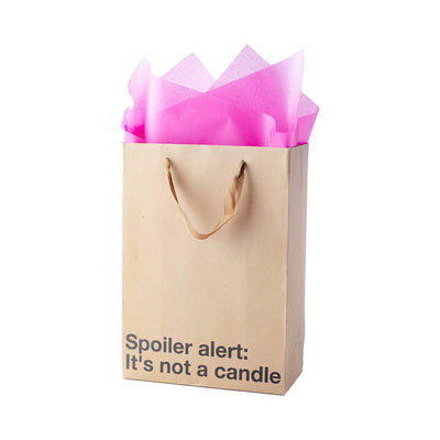 Kraft gift bag with brown ribbon handles and pink tissue paper, printed with "Spoiler alert: It's not a candle" text.