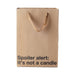 Kraft paper gift bag with brown ribbon handles and black text reading "Spoiler alert: It's not a candle" on front.