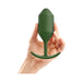 Hand holding a green silicone weighted snug plug with tapered tip and curved base for comfortable wear.