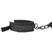 Close-up of black padded cuff with adjustable hook and loop strap and metal clasp attachment on white background.
