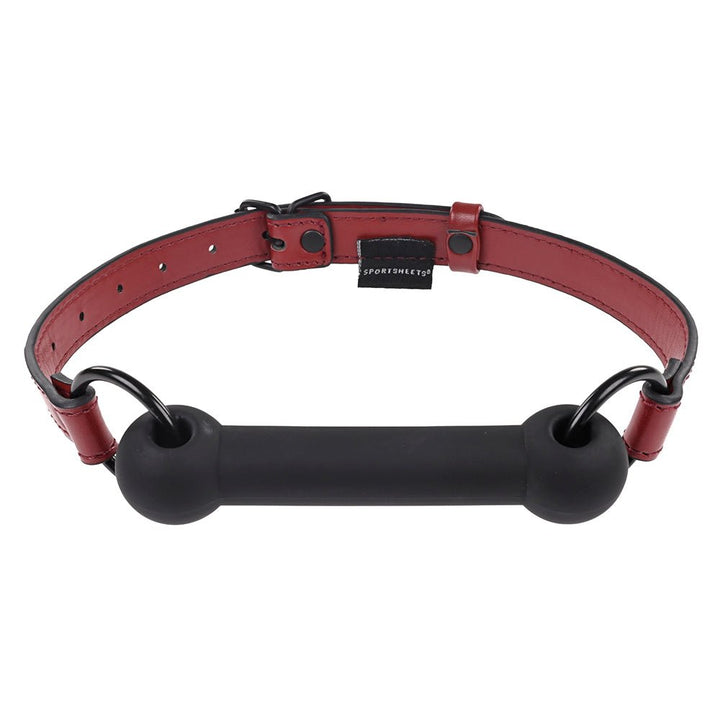 Adjustable red vegan leather strap bit gag with black silicone bar and metal rings by Sportsheets.