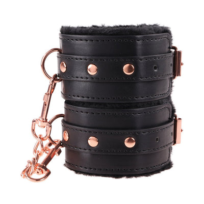 Black faux leather wrist restraints with plush lining and rose gold hardware, linked by a detachable chain clasp.