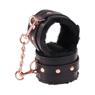 Black faux leather wrist restraints with soft plush lining and rose gold chain and hardware detail.