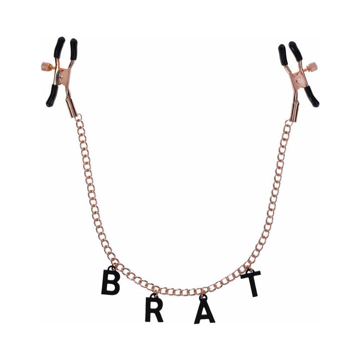 Rose gold nipple clamps with black rubber tips connected by a chain featuring black letter charms spelling BRAT.