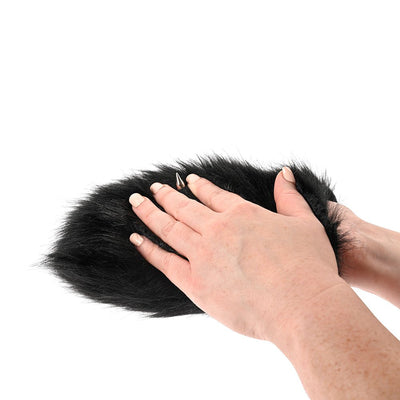 Hands demonstrating the black faux fur Sportsheets Spiked Sensory Mitt with one visible metal spike on a white background.