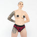 Model wearing a maroon and black EmEx contour harness with black nipple covers and detailed arm and thigh tattoos.