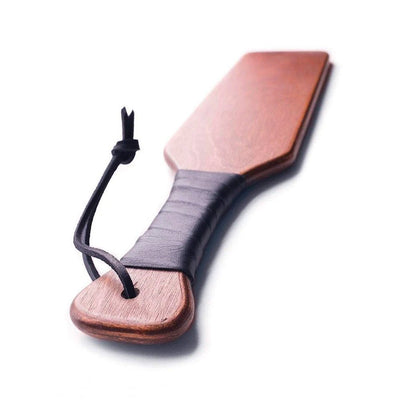 Leather wrapped wooden spanking paddle with wrist strap, polished finish and ergonomic handle for grip.