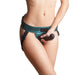 Close-up of a person wearing a teal leatherette strap-on harness with adjustable black straps and holding a black silicone dildo.