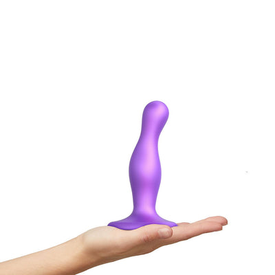 Hand holding a metallic purple curved silicone plug with a wide base and ergonomic shape.