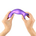 Hands holding and gently bending a metallic purple curved silicone plug with ergonomic design and suction base.